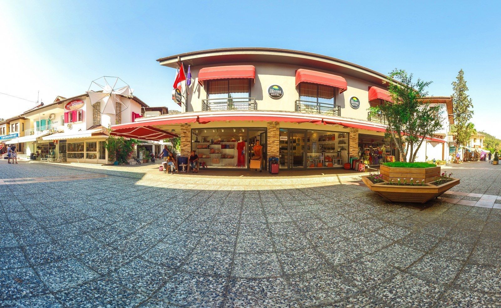 A hotel with a central atrium, outdoor seating, and a small garden area.