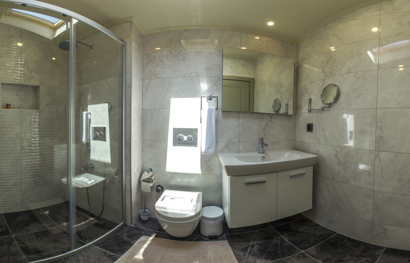 Une salle de bain moderne avec une douche à parois de verre, un lavabo avec un miroir et des toilettes.