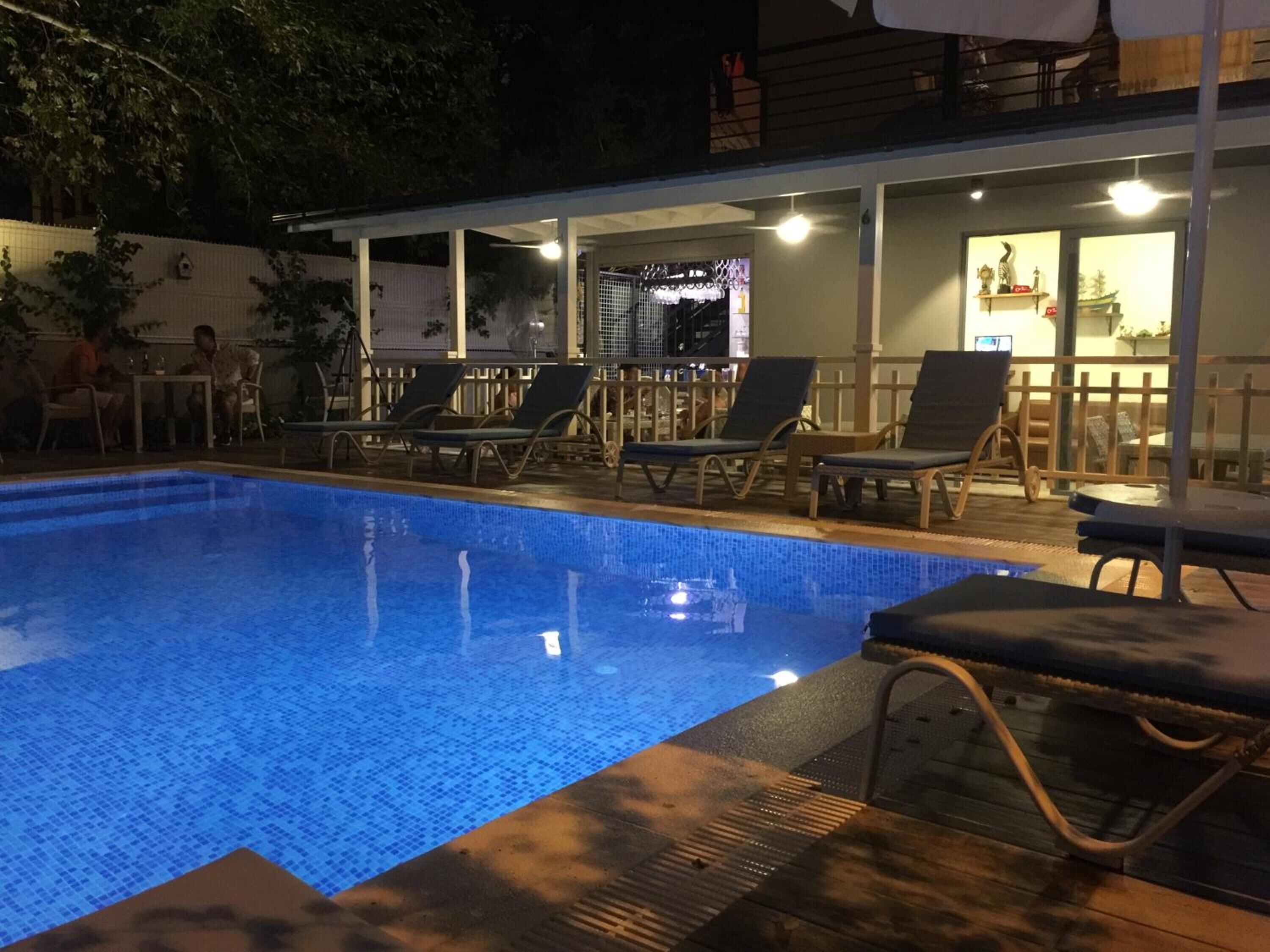 Une piscine avec des chaises longues et un espace abrité comprenant des tables et des chaises.