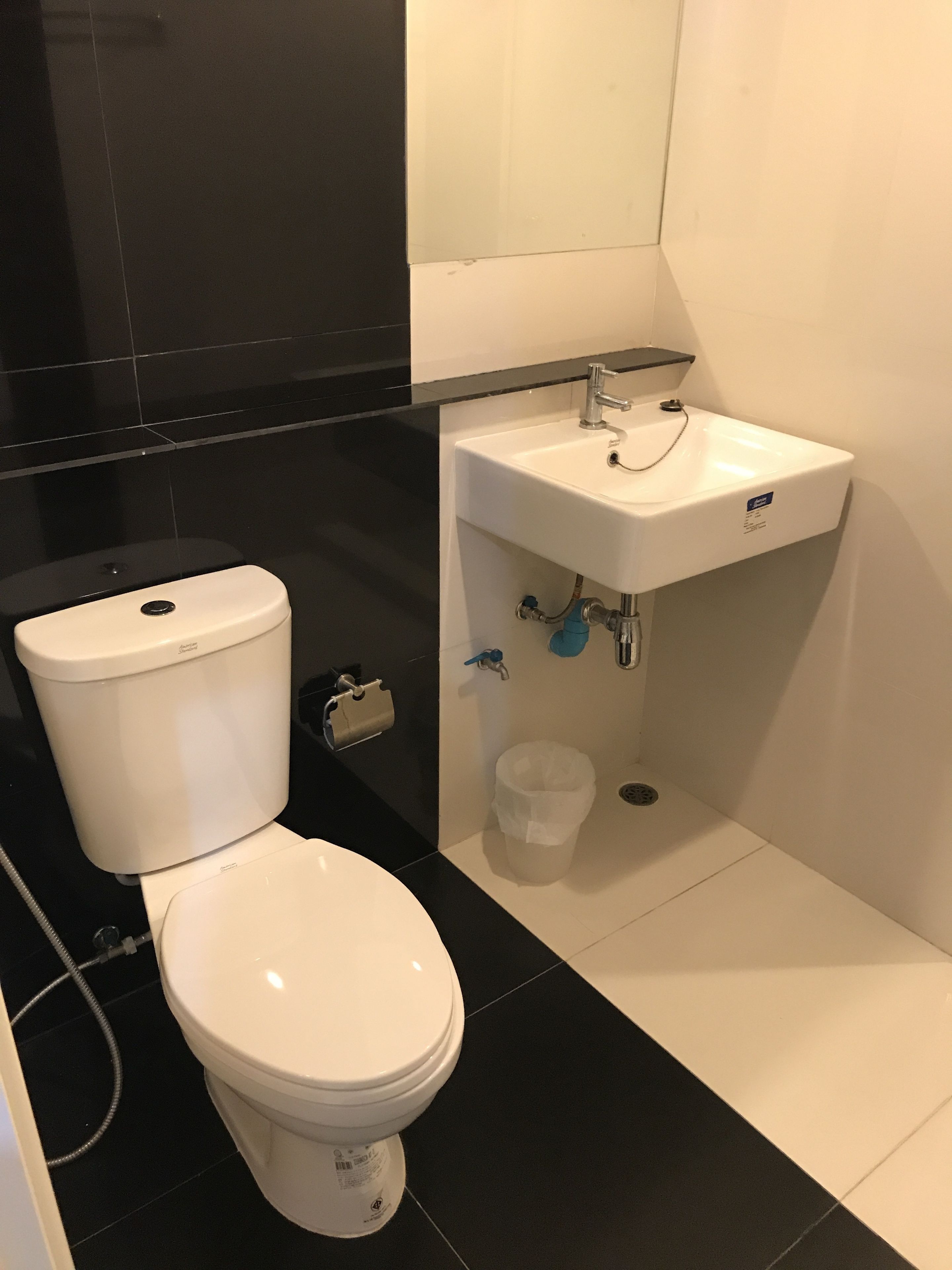 A bathroom with a white toilet, a sink, and a trash bin.