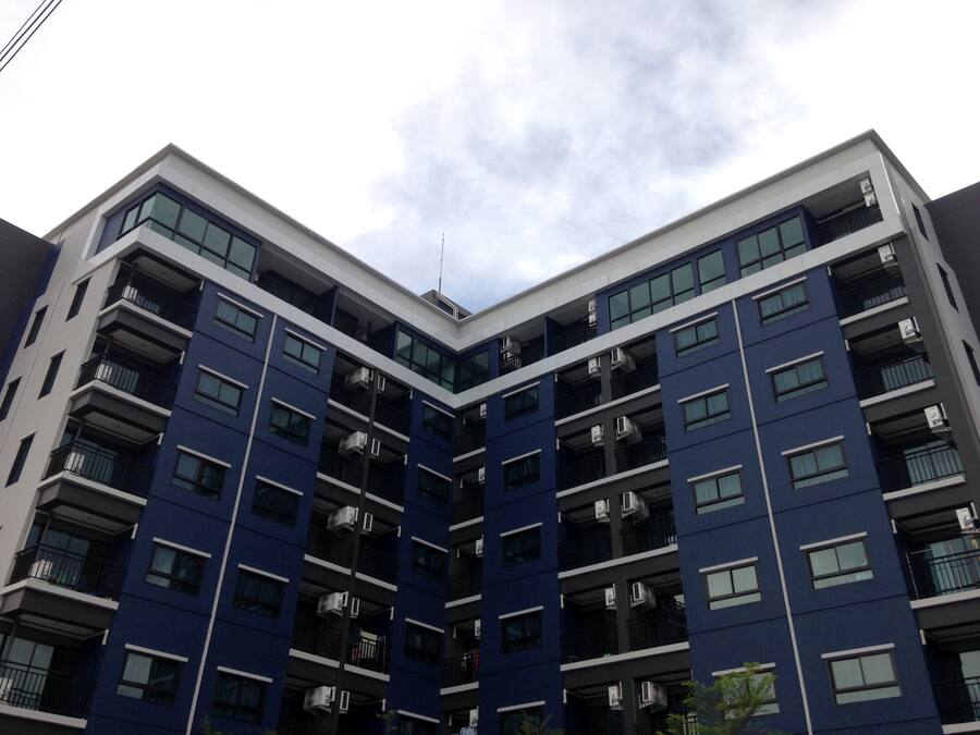 Un edificio residencial de varios pisos con balcones y unidades de aire acondicionado.