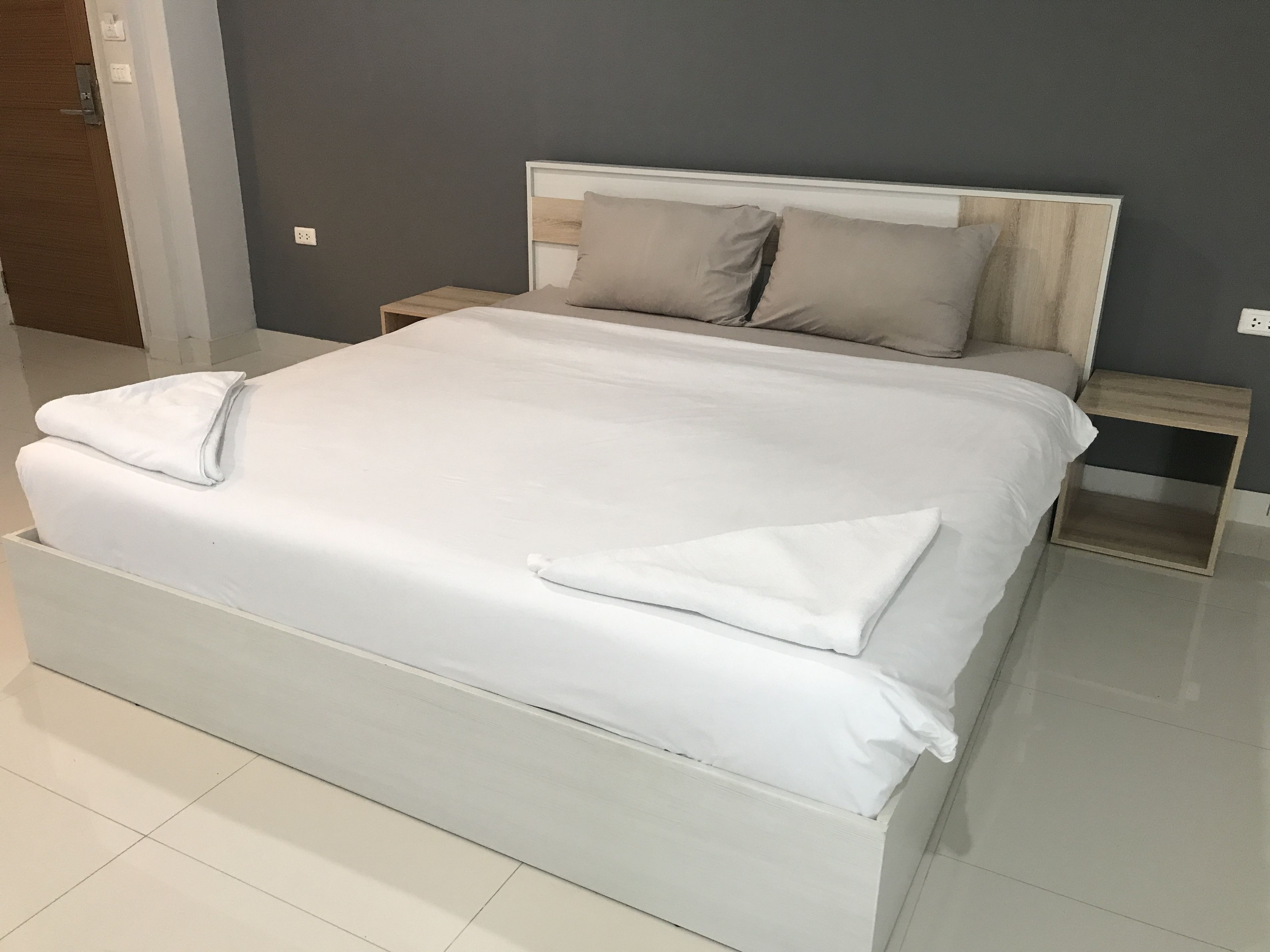 A large bed with white linens, a wooden headboard, and two bedside tables with lamps.