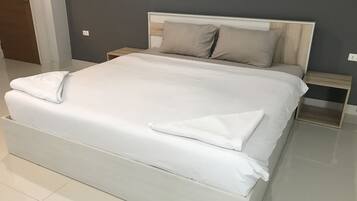 A large bed with white linens, a wooden headboard, and two bedside tables with lamps.