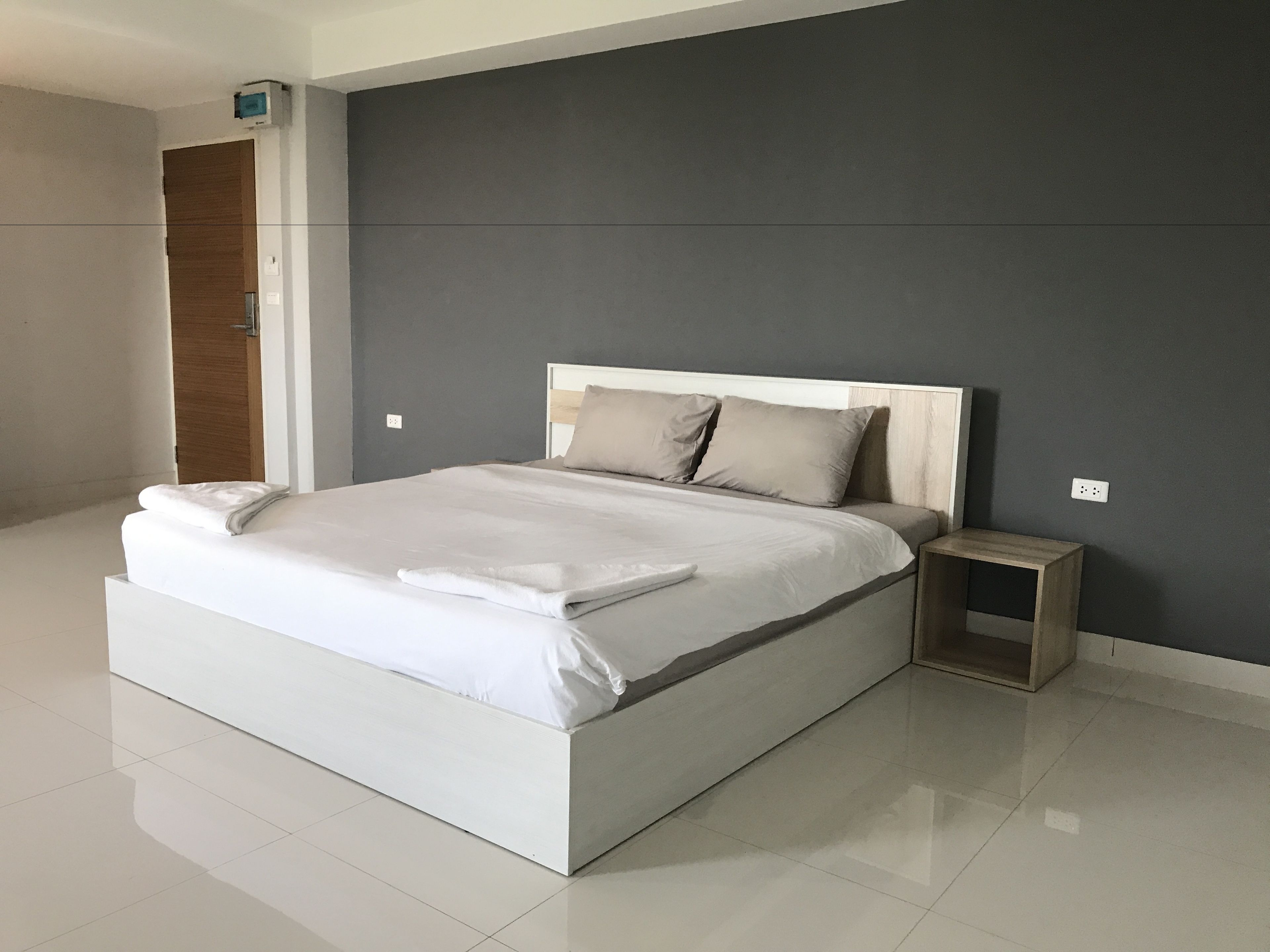 Un dormitorio moderno con una cama grande, una mesita de noche y una puerta de madera.