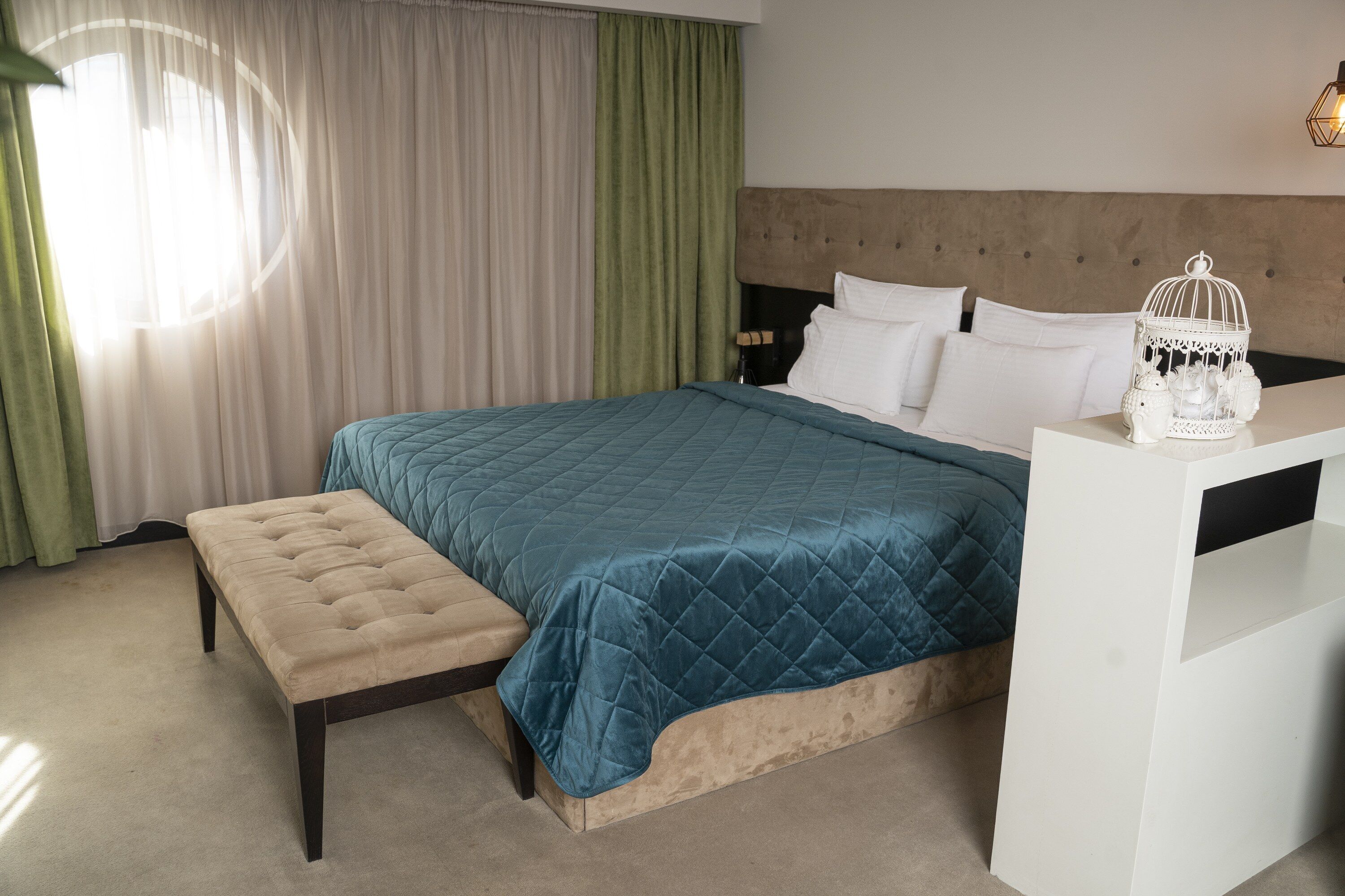 A bedroom with a bed, a bench, a nightstand, and a white dresser.