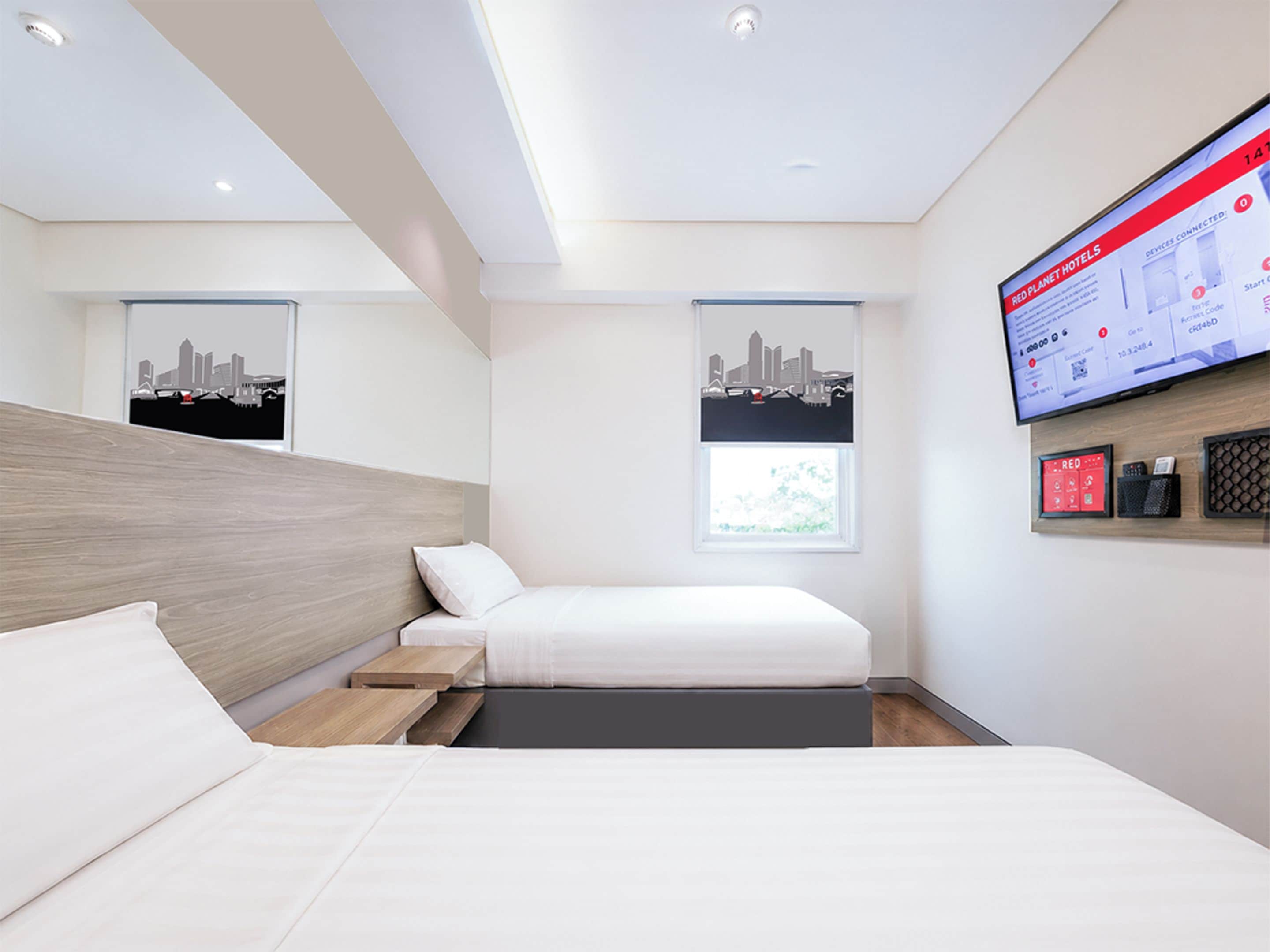 Una habitación de hotel moderna con una cama, un escritorio y un televisor montado que muestra la interfaz del hotel.