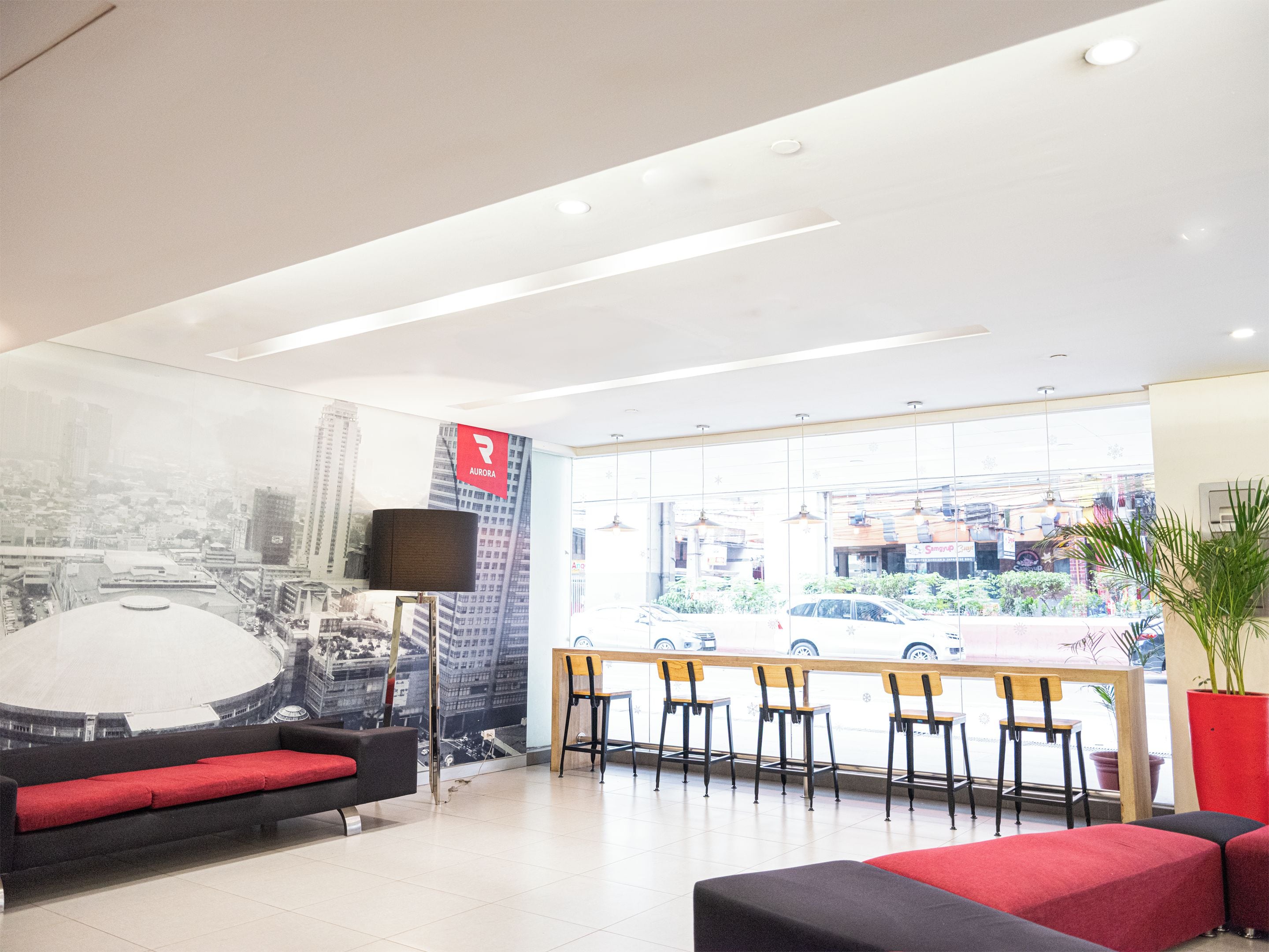 A modern interior with a large window, a red couch, and a cityscape mural.