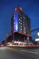 Un hotel de varios pisos con un cartel rojo y azul llamativo en la parte superior.