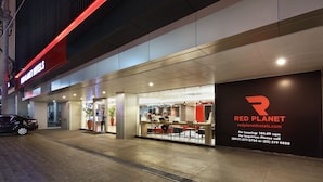 A modern hotel exterior with a prominent Red Planet sign, a seating area outside, and a visible entrance. - Red Planet Cubao Aurora Boulevard (Quezon City)