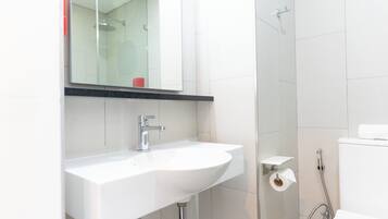 Un bany modern amb un lavabo blanc, un mirall al damunt, una zona de dutxa i un vàter.