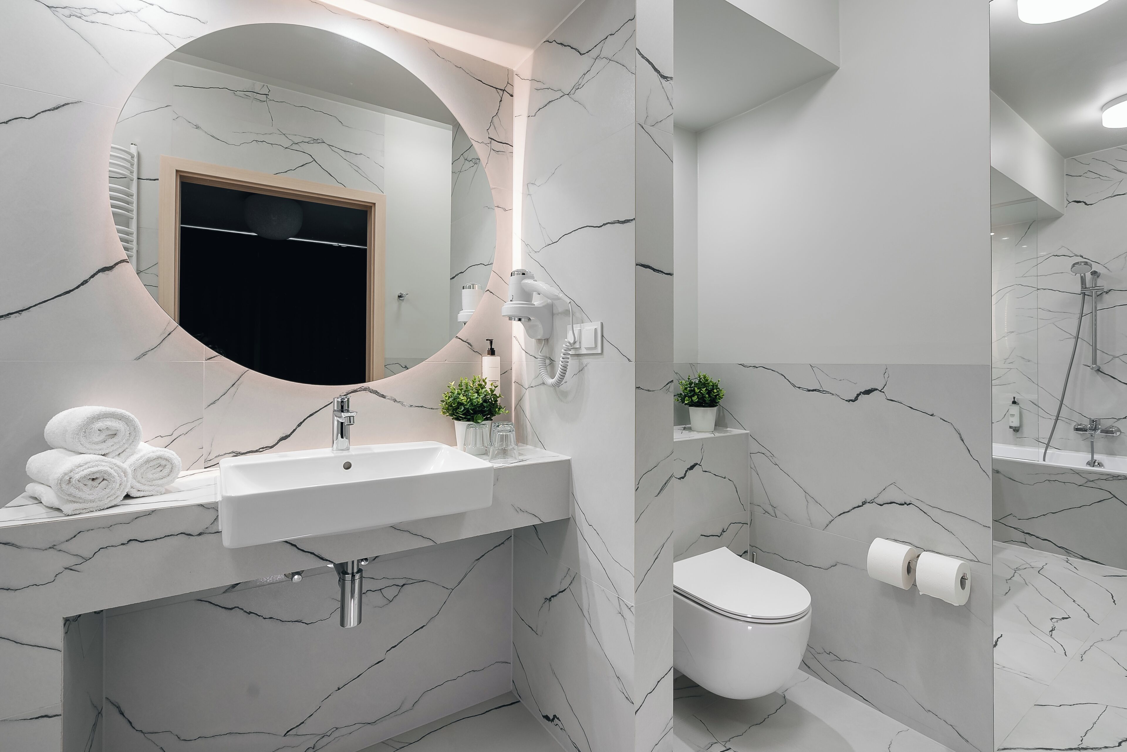 Une salle de bain moderne avec un lavabo en marbre, des toilettes et un espace douche.
