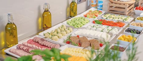 Un bufé con diversos alimentos, incluyendo carnes, quesos y verduras.