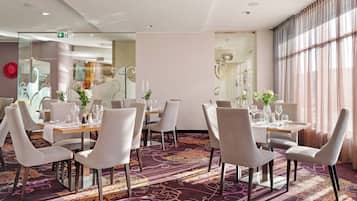 Un comedor de hotel con mesas redondas, sillas y una alfombra estampada.