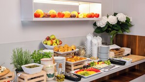 Ein reichhaltiges Buffet mit verschiedenen Speisen, darunter Obst, Gebäck und Soßen.