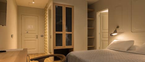 Un dormitorio con una cama, una silla de madera, un armario y un escritorio.