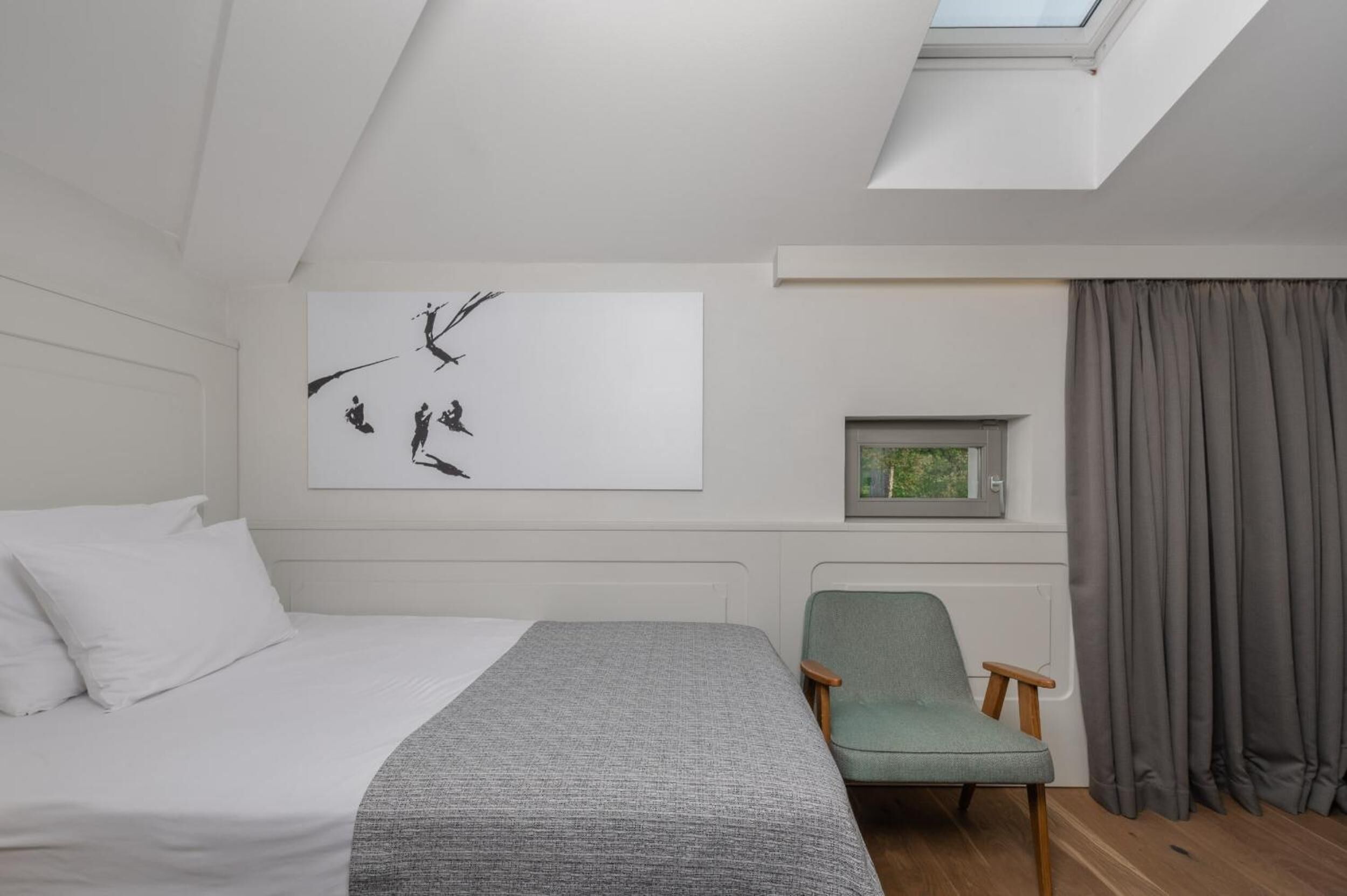 Une chambre à coucher avec un lit, une chaise, une fenêtre et un tableau accroché au mur.