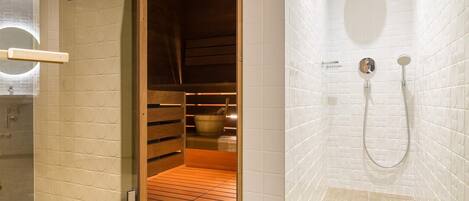 A bathroom with a wooden sauna, a shower, and a tiled wall.