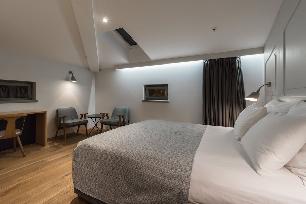 Ein modernes Hotelzimmer mit einem großen Bett, einem Schreibtisch, zwei Stühlen und einem kleinen Tisch.
