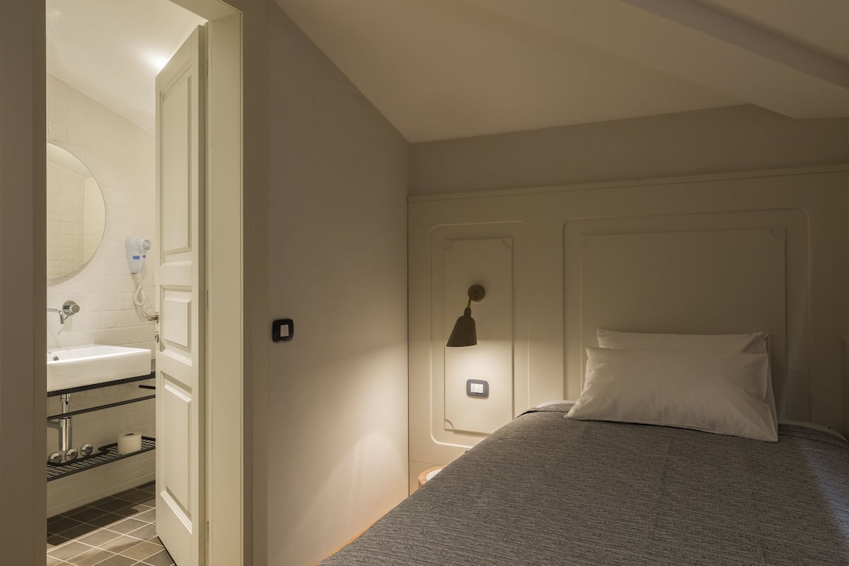 Ein Schlafzimmer mit einem Bett, einem Nachttisch, einer Wandlampe und einer Tür.