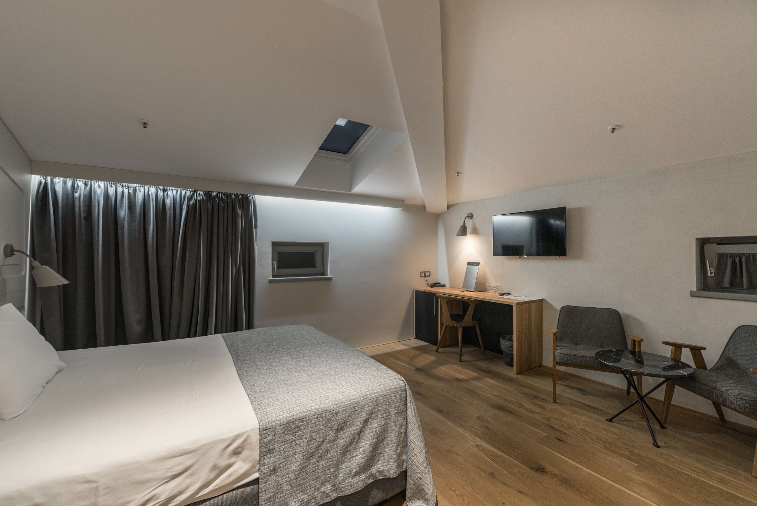 A modern hotel room with a bed, desk, and seating area.