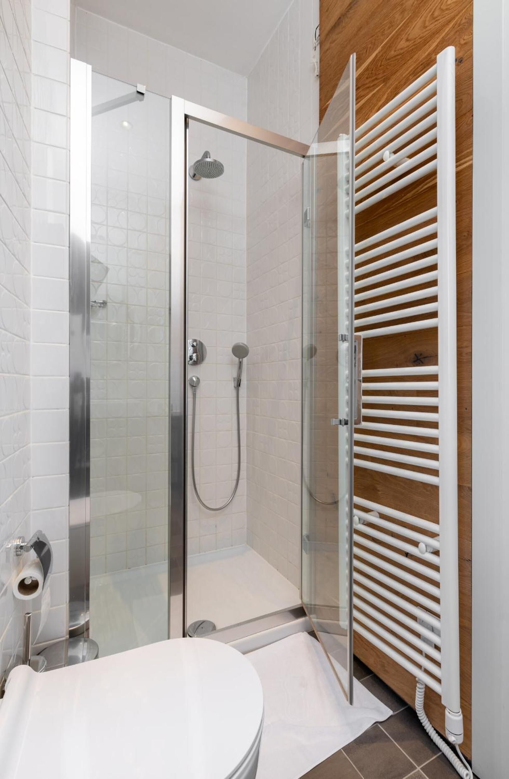 Ein modernes Badezimmer mit einer Duschkabine aus Glas, einer weißen Toilette und einer Wandverkleidung aus Holz.