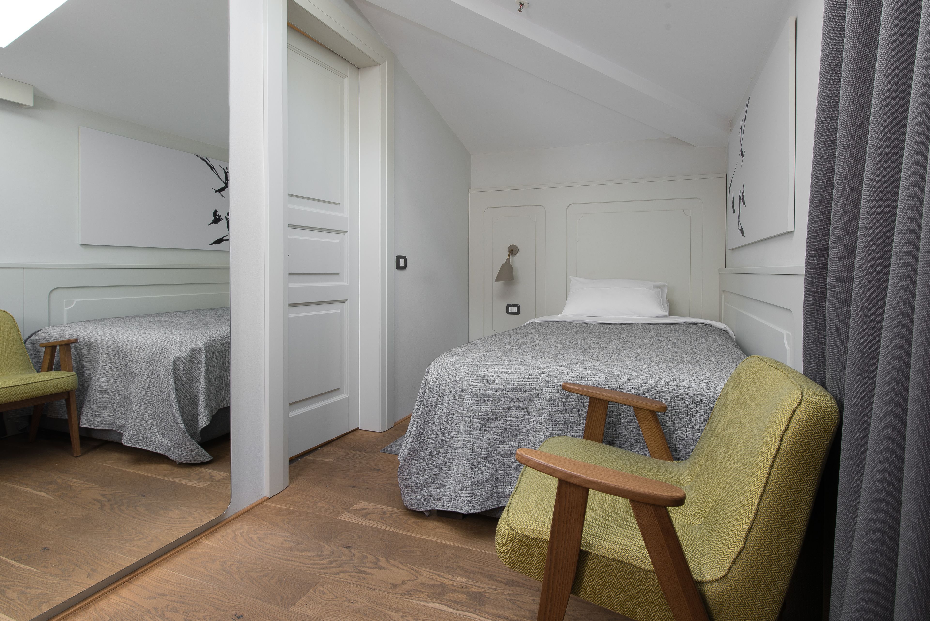A bedroom with a bed, a chair, and a door leading to another room.