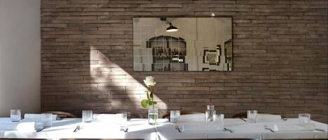 A dining area with wooden tables and chairs, a brick wall, and pendant lighting.