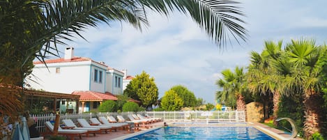 Een buitenzwembad, parasols bij het zwembad en ligstoelen