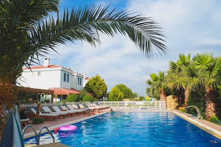 Una piscina al aire libre, sombrillas, sillones reclinables de piscina. Destina Suit Hotel