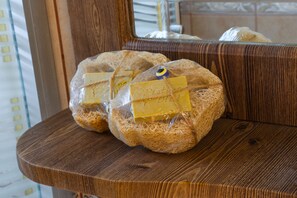 Two loaves of bread wrapped in plastic on a wooden surface. - Destina Suit Hotel (Bozcaada)