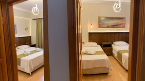 A hotel room with two beds, a painting on the wall, and a wooden headboard. - Destina Suit Hotel (Bozcaada)
