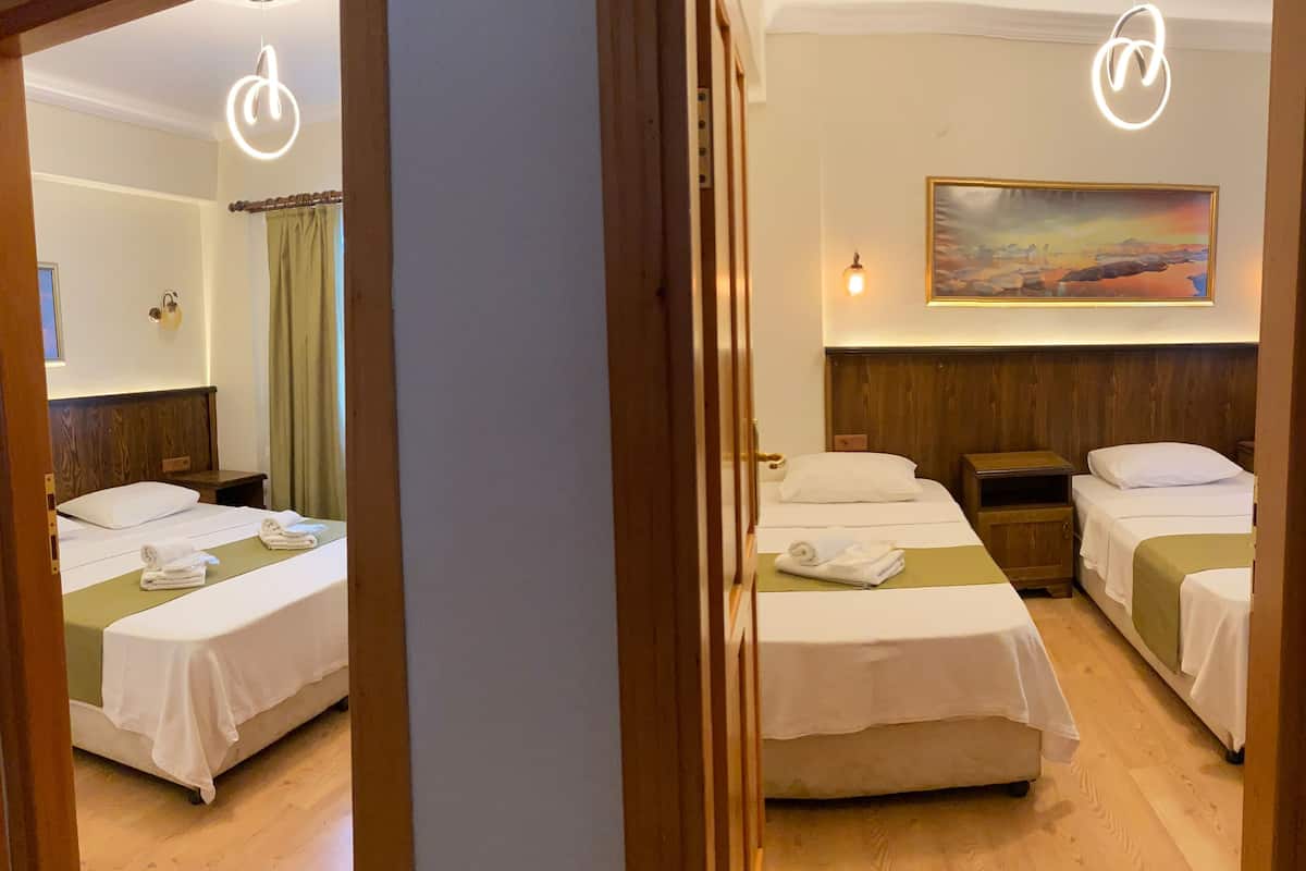 A hotel room with two beds, a painting on the wall, and a wooden headboard.
