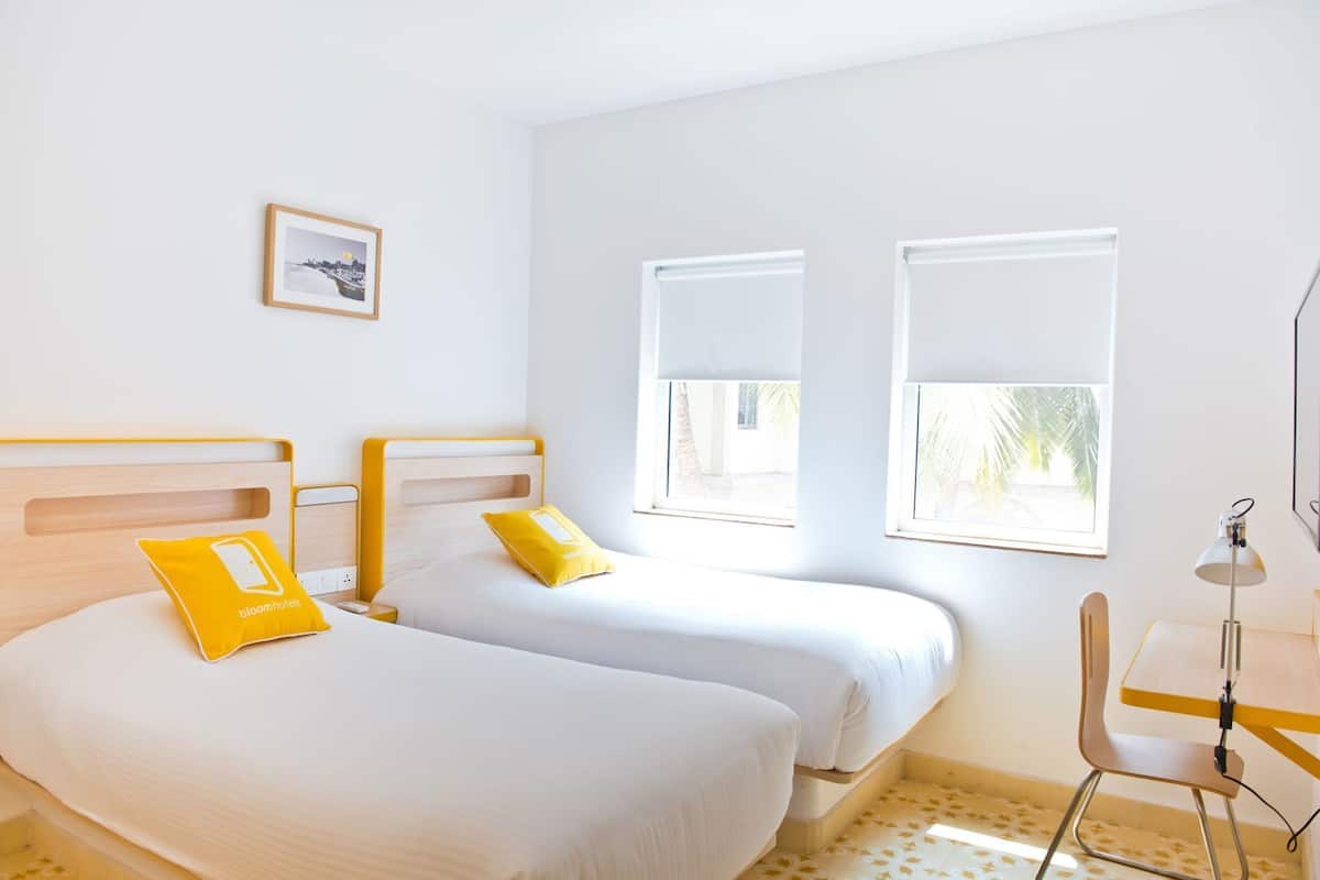 Habitación de hotel con dos camas, un escritorio y dos ventanas.