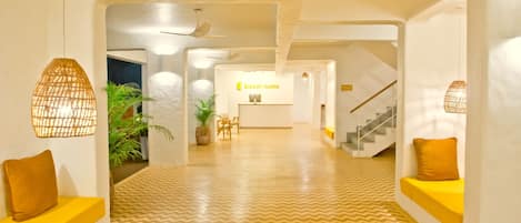 A modern hotel lobby with a chevron-patterned floor, a reception desk, and a staircase.