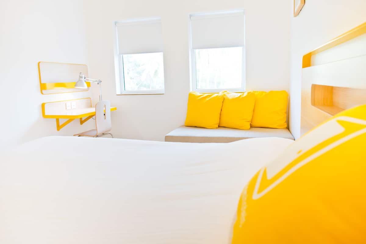 A bright room with a bed, a desk, and two windows.