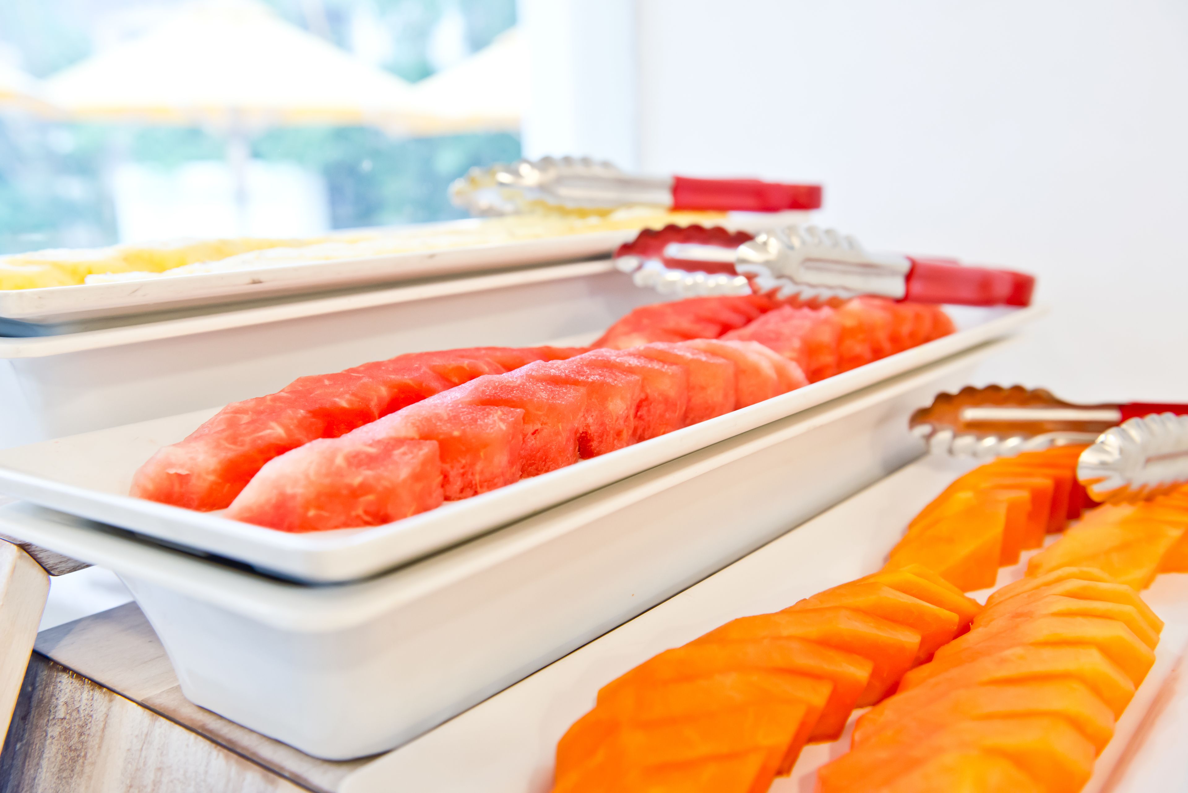 Un buffet proposant une variété de plats, notamment des tranches de pastèque et d’orange.