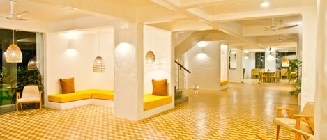 A modern hotel lobby with a chevron-patterned floor, seating areas with yellow cushions, and pendant lighting.