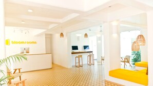 A modern hotel lobby with a reception desk, bar area, seating, and a patterned floor. - Bloom Hotel – Calangute (Calangute)