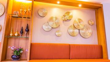 A modern interior with a wooden shelf displaying decorative items, a cushioned seating area, and wall-mounted circular patterns.