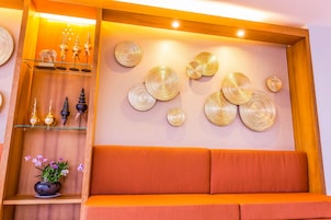 A modern interior with a wooden shelf displaying decorative items, a cushioned seating area, and wall-mounted circular patterns.