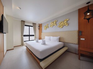 A hotel room with a large bed, a TV mounted on the wall, and a window with curtains. - The Signature Hotel Thapae (Chiang Mai)