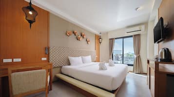 Habitación de hotel con una cama grande, un escritorio, una silla, un televisor y una ventana con vistas a la ciudad.