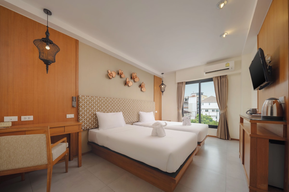 A hotel room with a large bed, a desk, a television, and a view of the city.