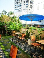 An outdoor patio with stone flooring, wooden tables, and chairs.