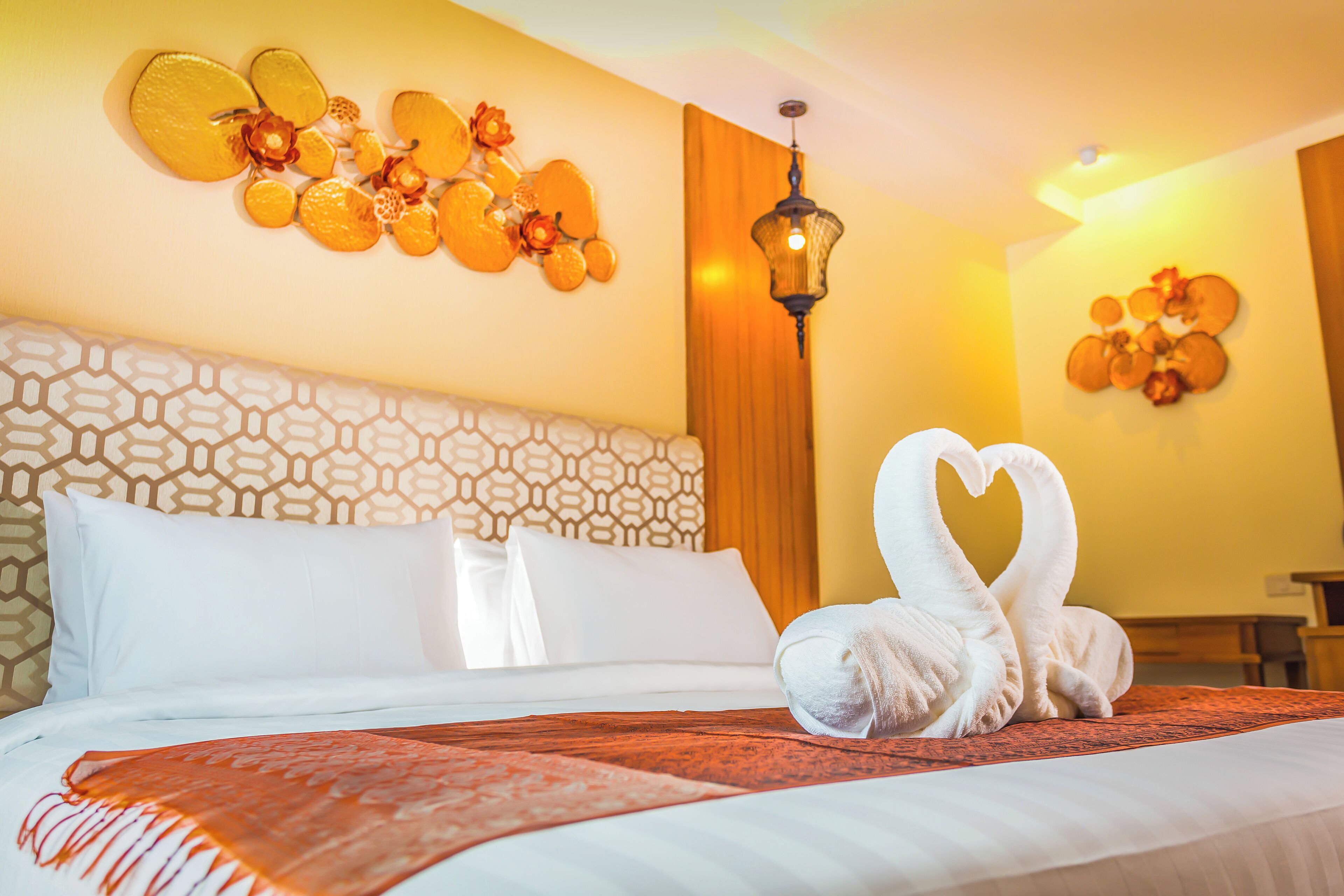 Ein Hotelzimmer mit einem Bett, einem Wandbild und einer dekorativen Handtuchgestaltung.