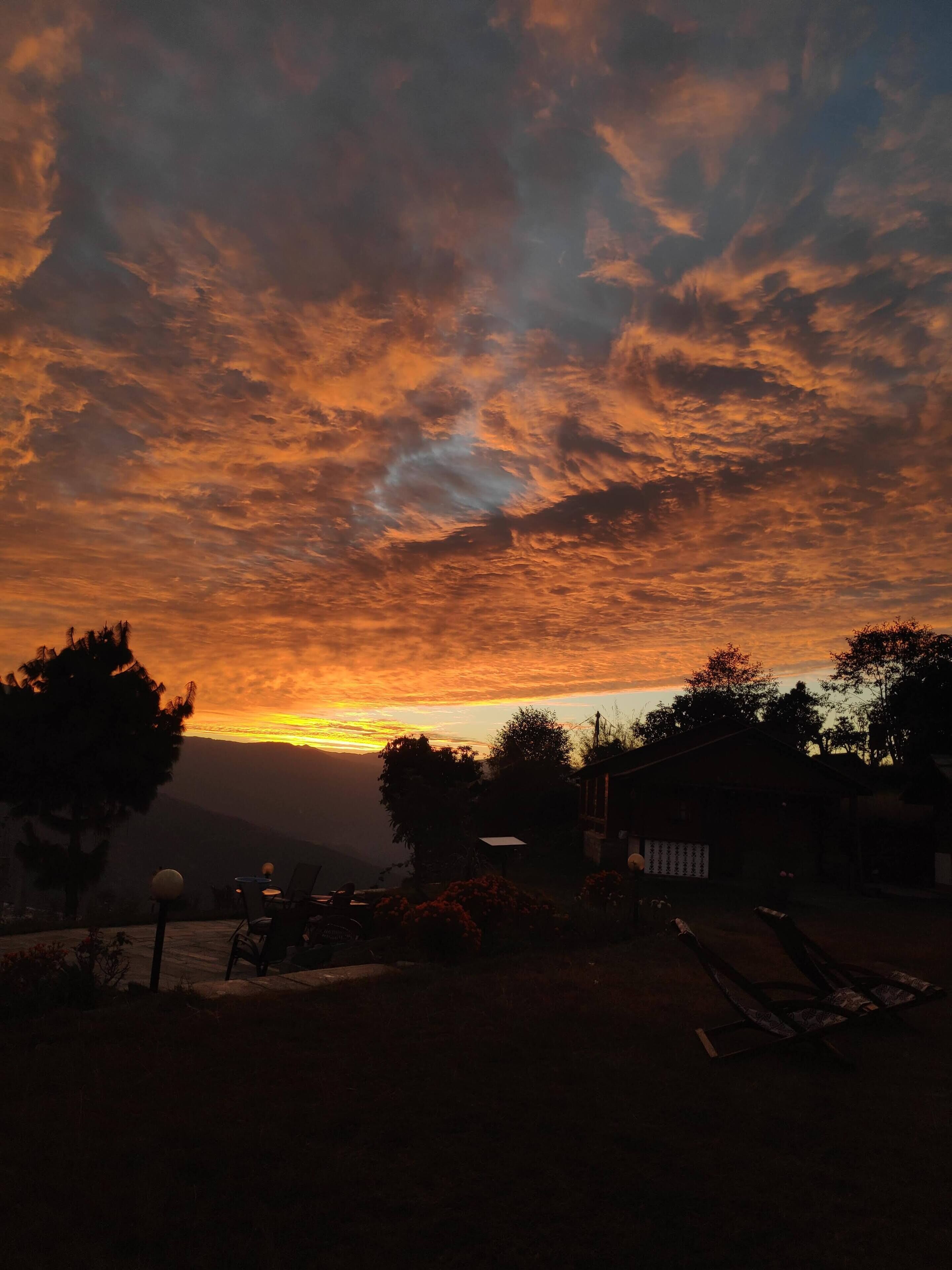Una vista al atardecer con cielo despejado, algunos árboles y un edificio en primer plano.