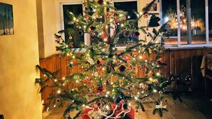 Un árbol de Navidad decorado en una habitación con suelo de piedra y paredes de madera.