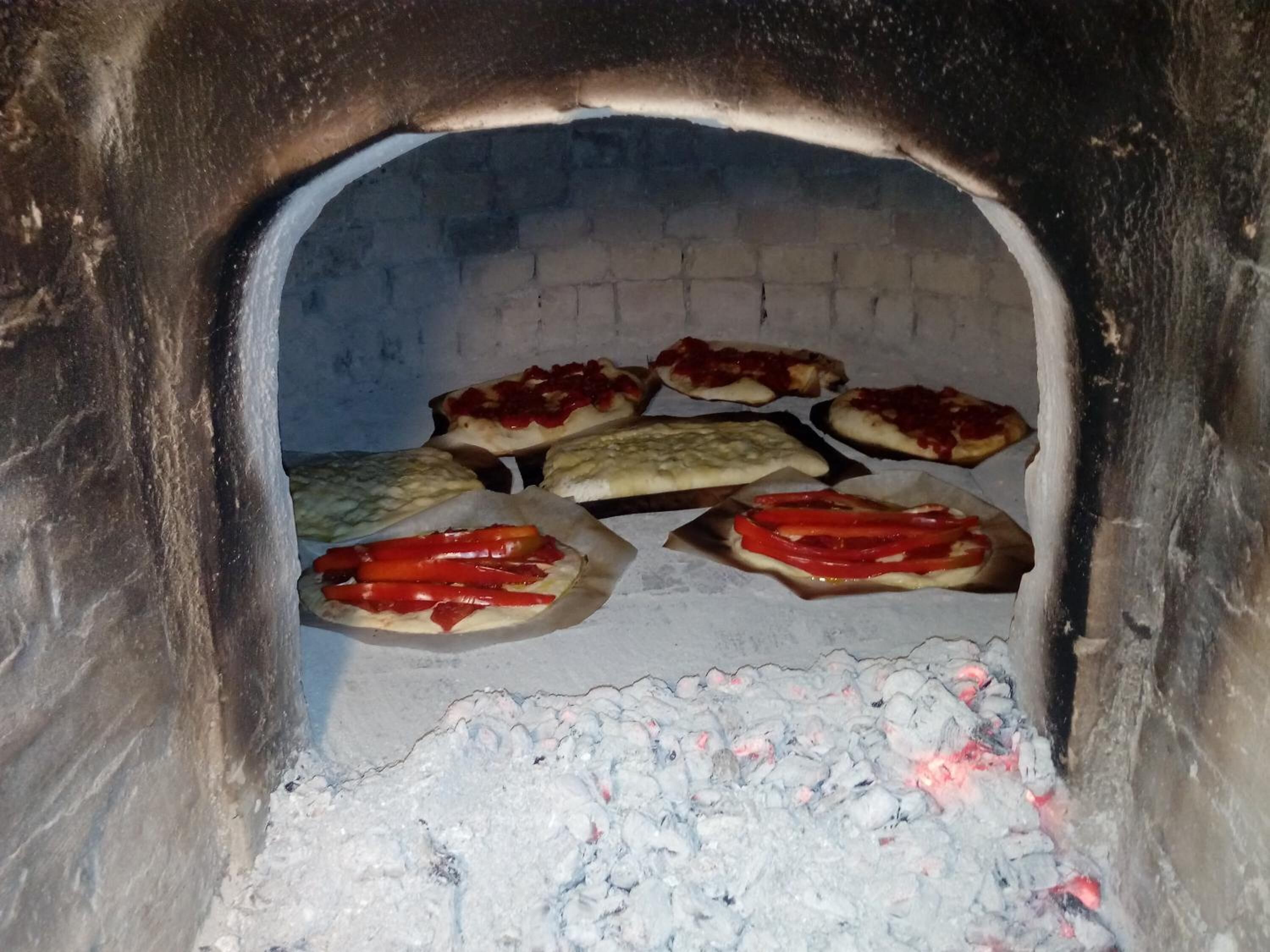 A brick oven with pizzas baking inside.