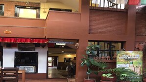 A hotel entrance with a red awning, potted plants, and a sign that reads "ENJOY LIFE'S SIMPLE MOMENTS." - Cafe de Patan (Lalitpur)