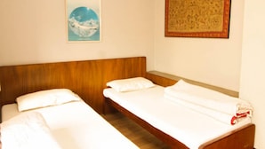 A room with two single beds, a wooden headboard, a framed map on the wall, and a poster with text. - Cafe de Patan (Lalitpur)
